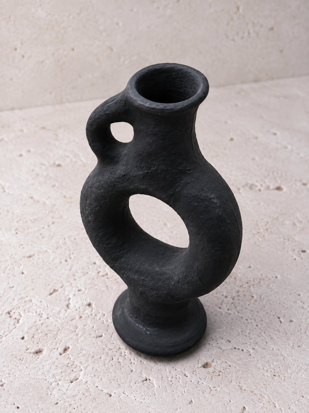 Détail de la texture volcanique rugueuse du vase Obsidian noir mat