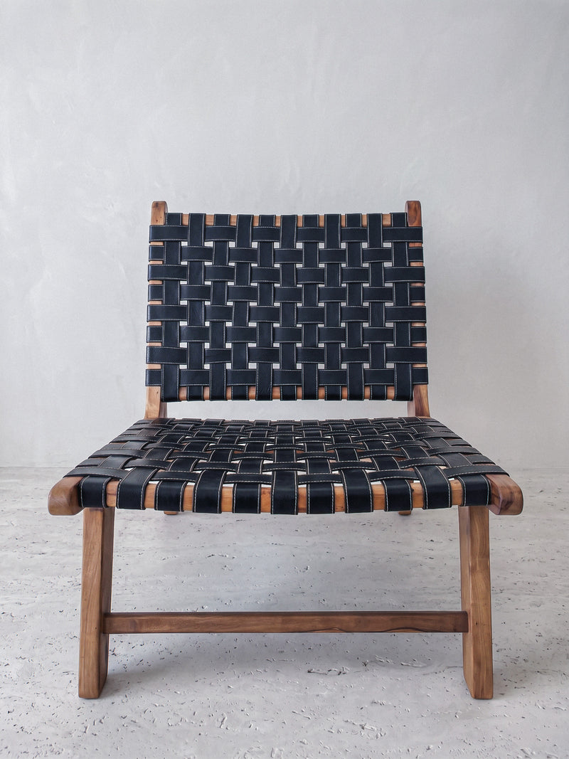 Mid-century modern lounge chair made of solid walnut wood and black woven leather straps.