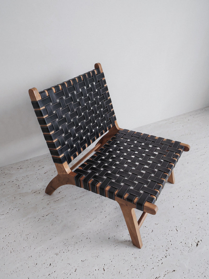 Mid-century modern lounge chair made of solid walnut wood and black woven leather straps.