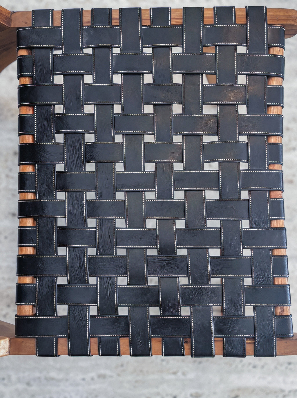 Mid-century modern lounge chair made of solid walnut wood and black woven leather straps.