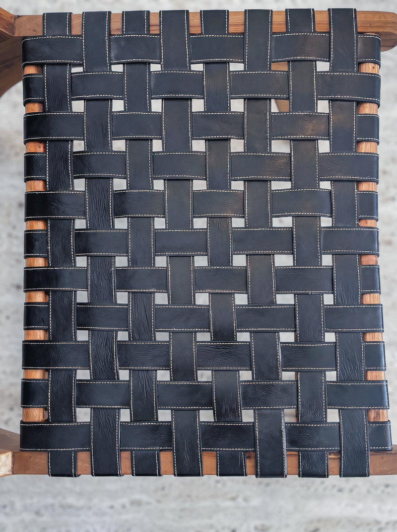 Mid-century modern lounge chair made of solid walnut wood and black woven leather straps.
